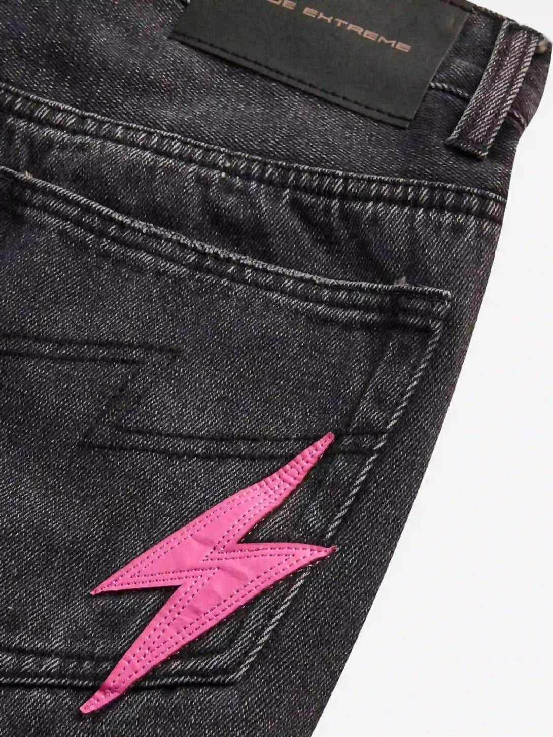 Zoomed-in view of TALISHKO jeans with a pink lightning bolt on the back pocket for edgy style.