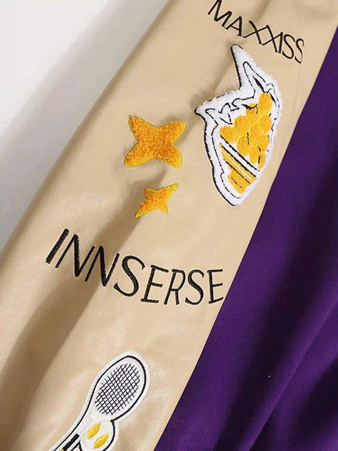 Intricate embroidery details on TALISHKO's retro baseball jacket sleeve, featuring unique patches.