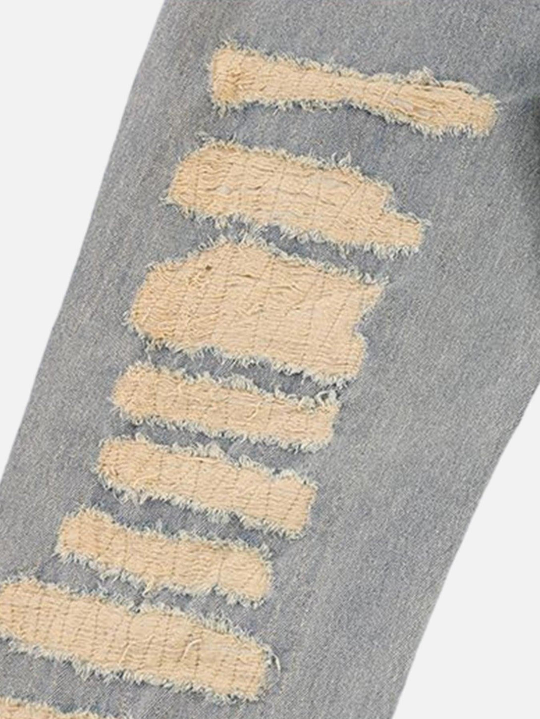 A tight crop highlighting TALISHKO's ripped denim texture with frayed detailing.
