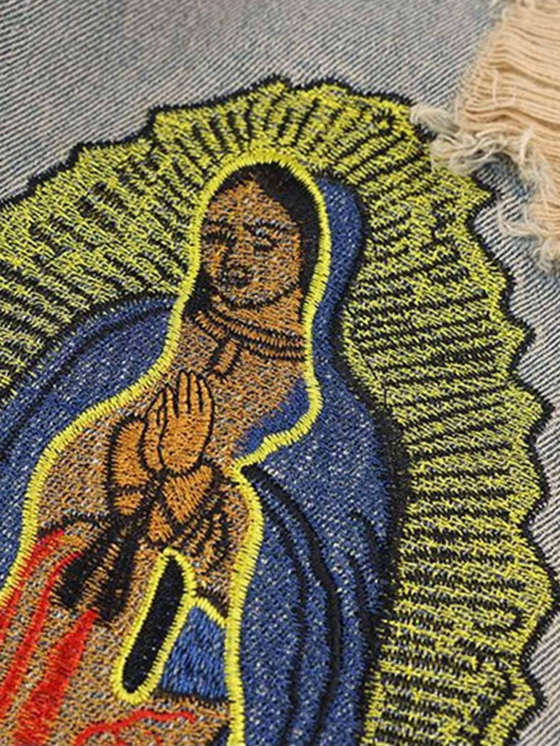 Intricate look at TALISHKO's religious patch on distressed denim, highlighting vibrant texture.