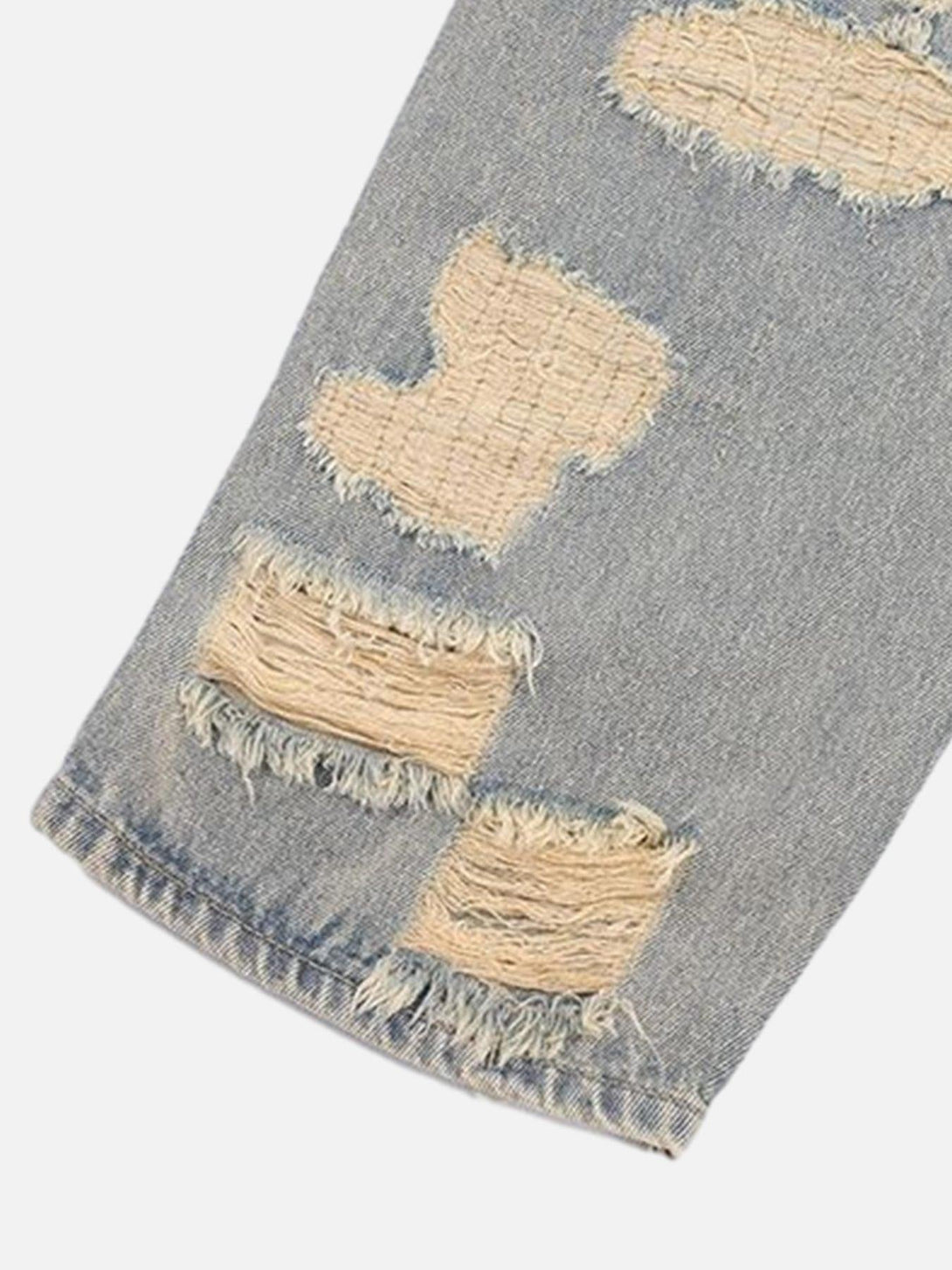 Detailed view of TALISHKO's ripped jeans, highlighting the frayed and distressed texture.