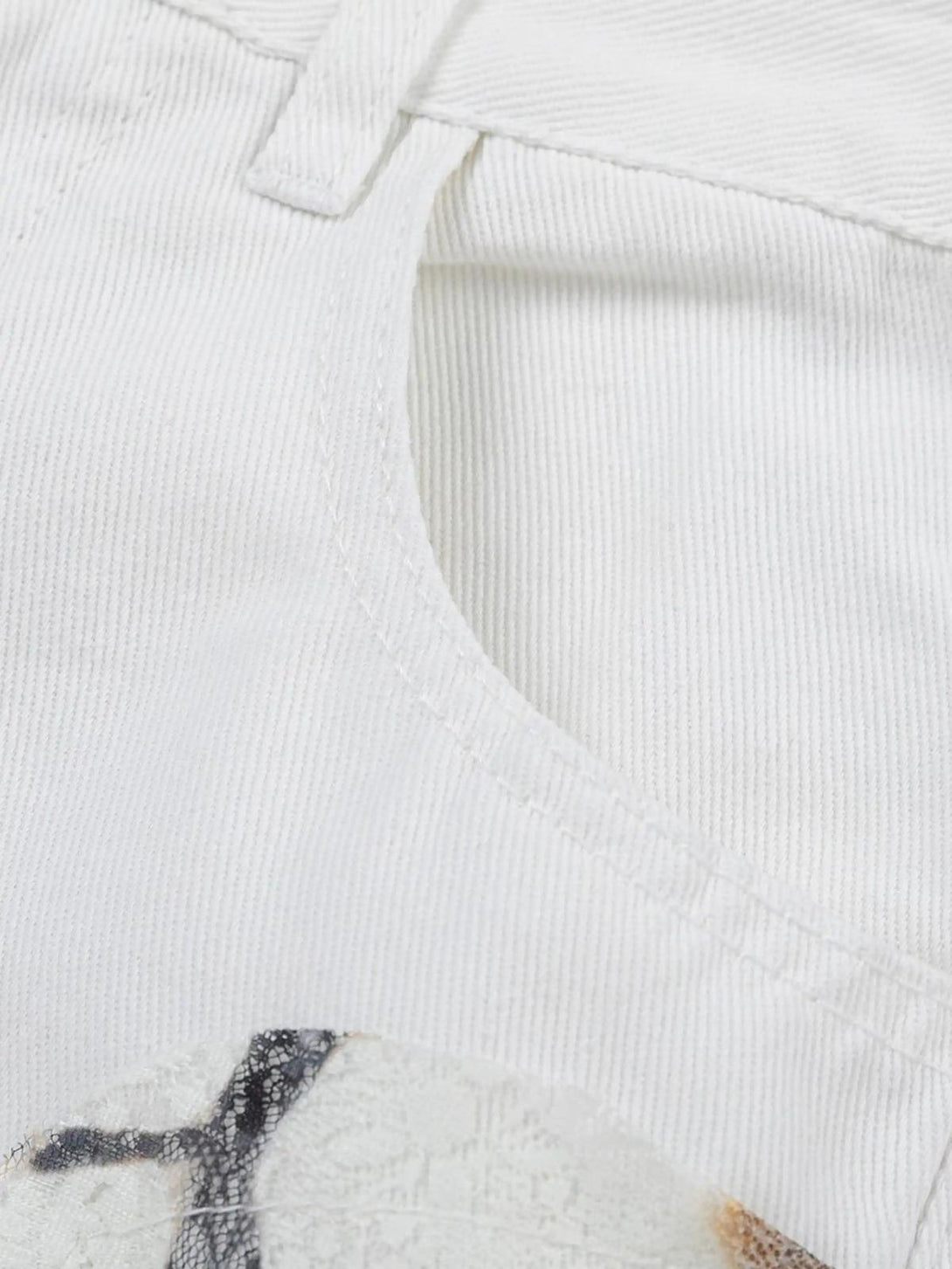 TALISHKO jeans detail, showcasing intricate white fabric texture and unique patch design.