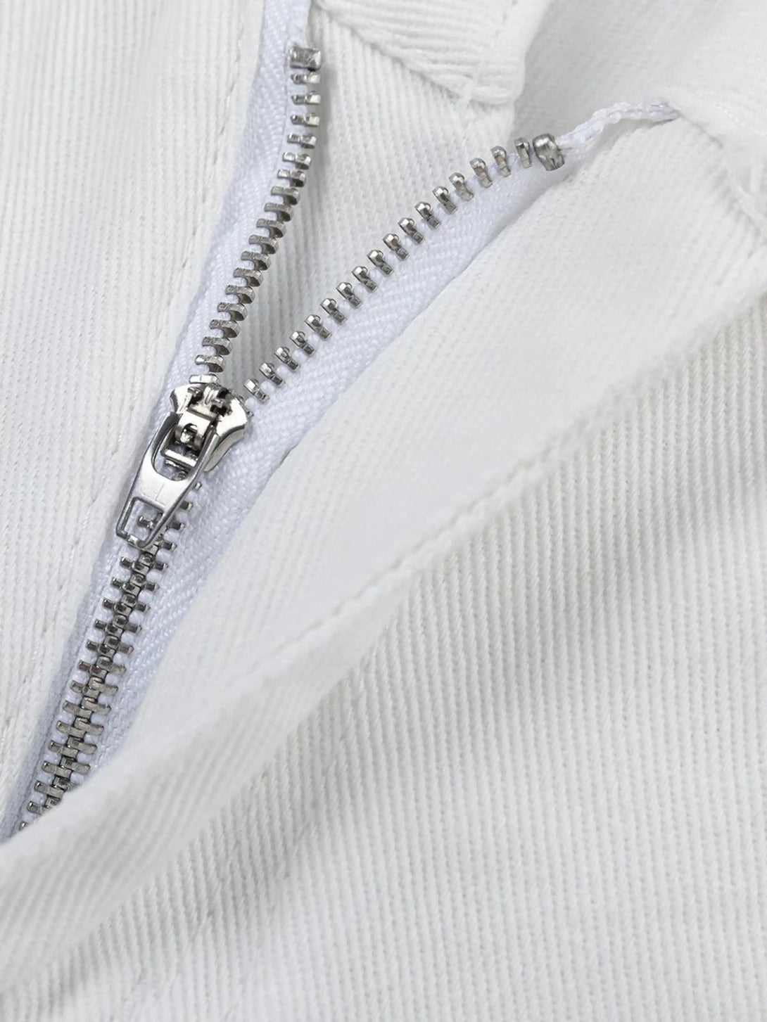 A detailed view of TALISHKO's street-style patch jeans zipper, highlighting quality craftsmanship.