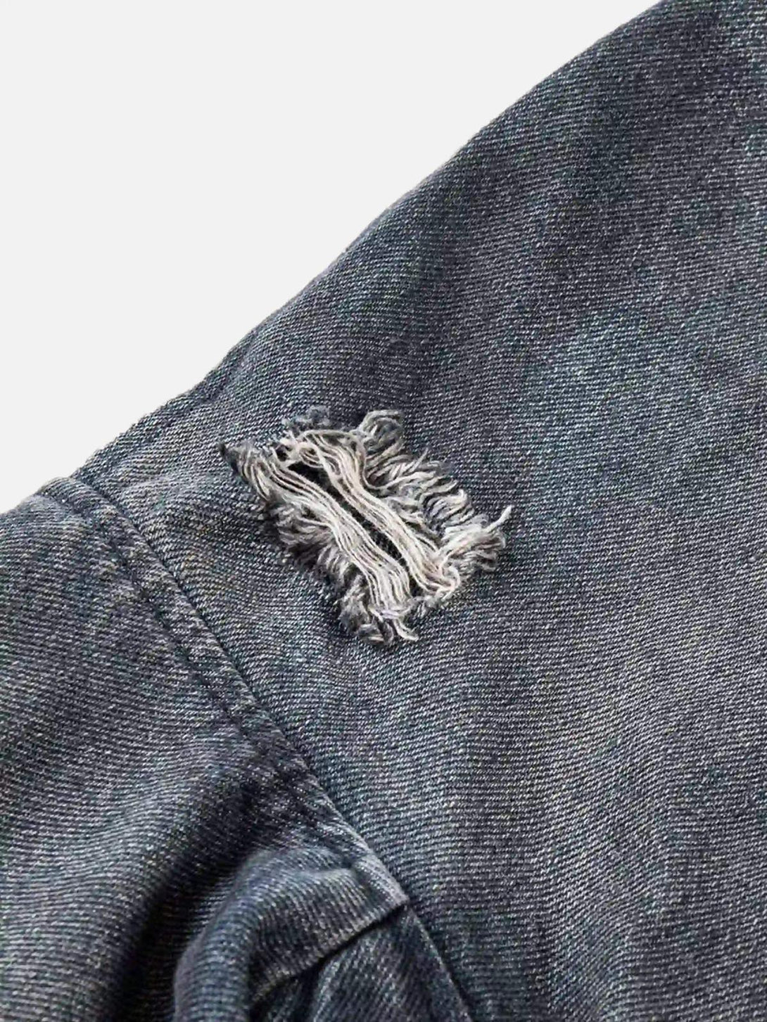 A textured close-up of the distressed shoulder detail on a TALISHKO retro hoodie.