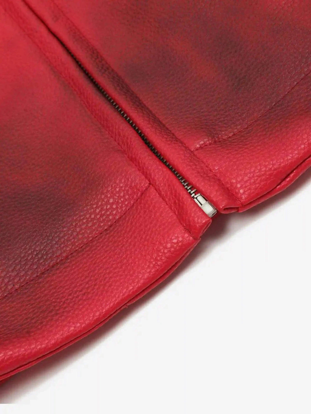 "Zoomed-in view of TALISHKO's red motorcycle jacket, showcasing textured leather and zipper."