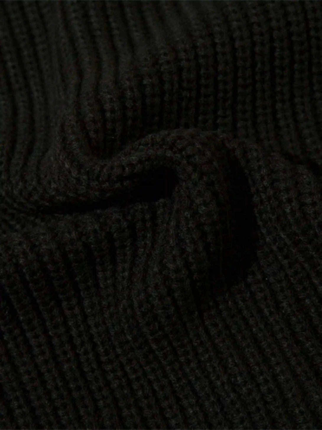 A tight crop showing TALISHKO's cardigan ribbed knit texture in black, highlighting intricate detail.