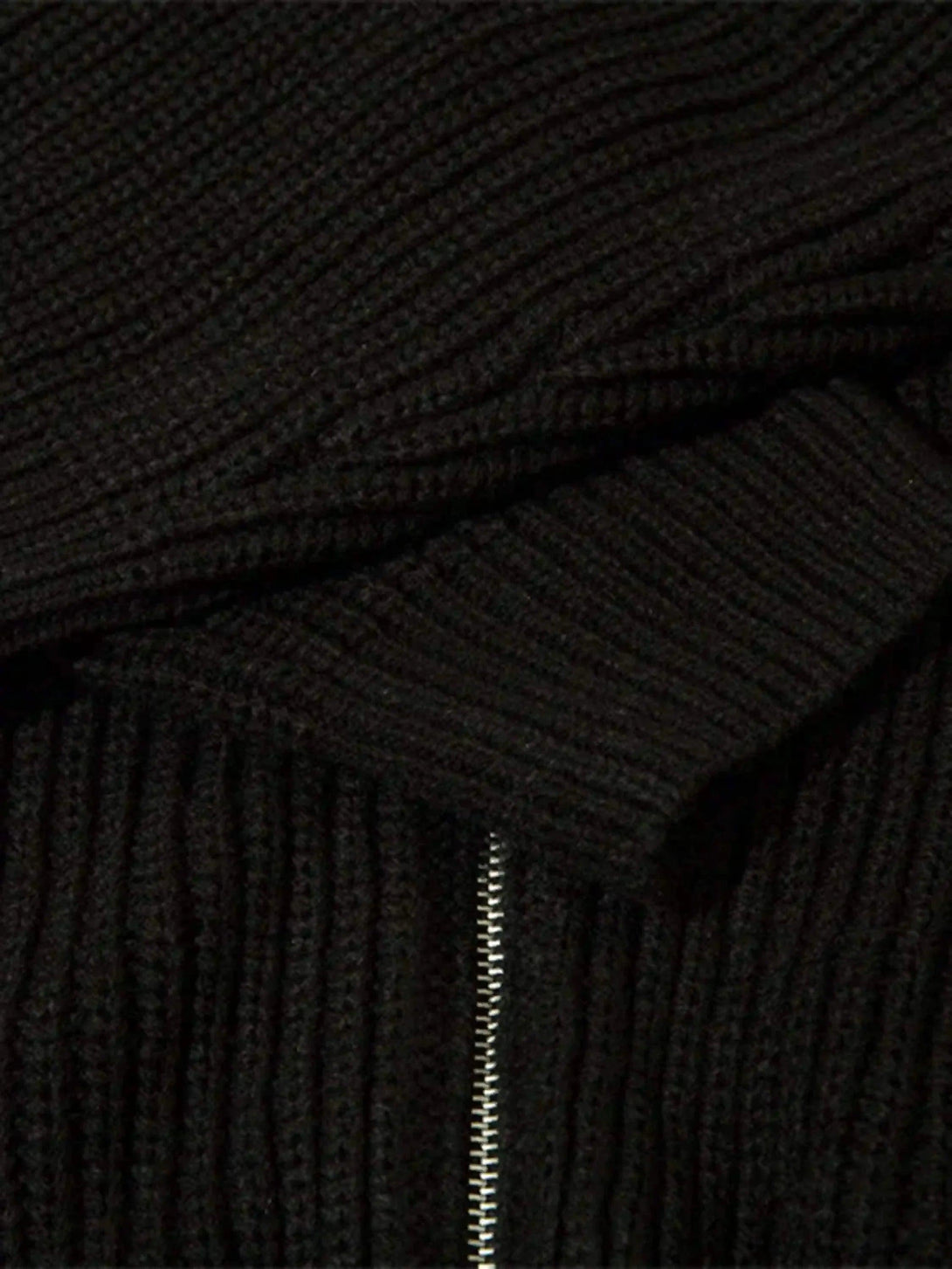 A tight crop highlighting TALISHKO's black cardigan zipper and ribbed texture.