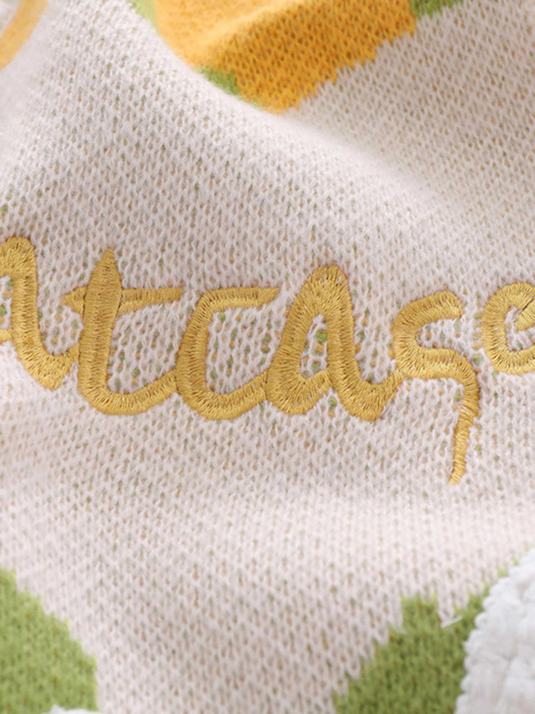 Detailed fabric and stitching on a sweater vest with embroidery by TALISHKO, showcasing texture.