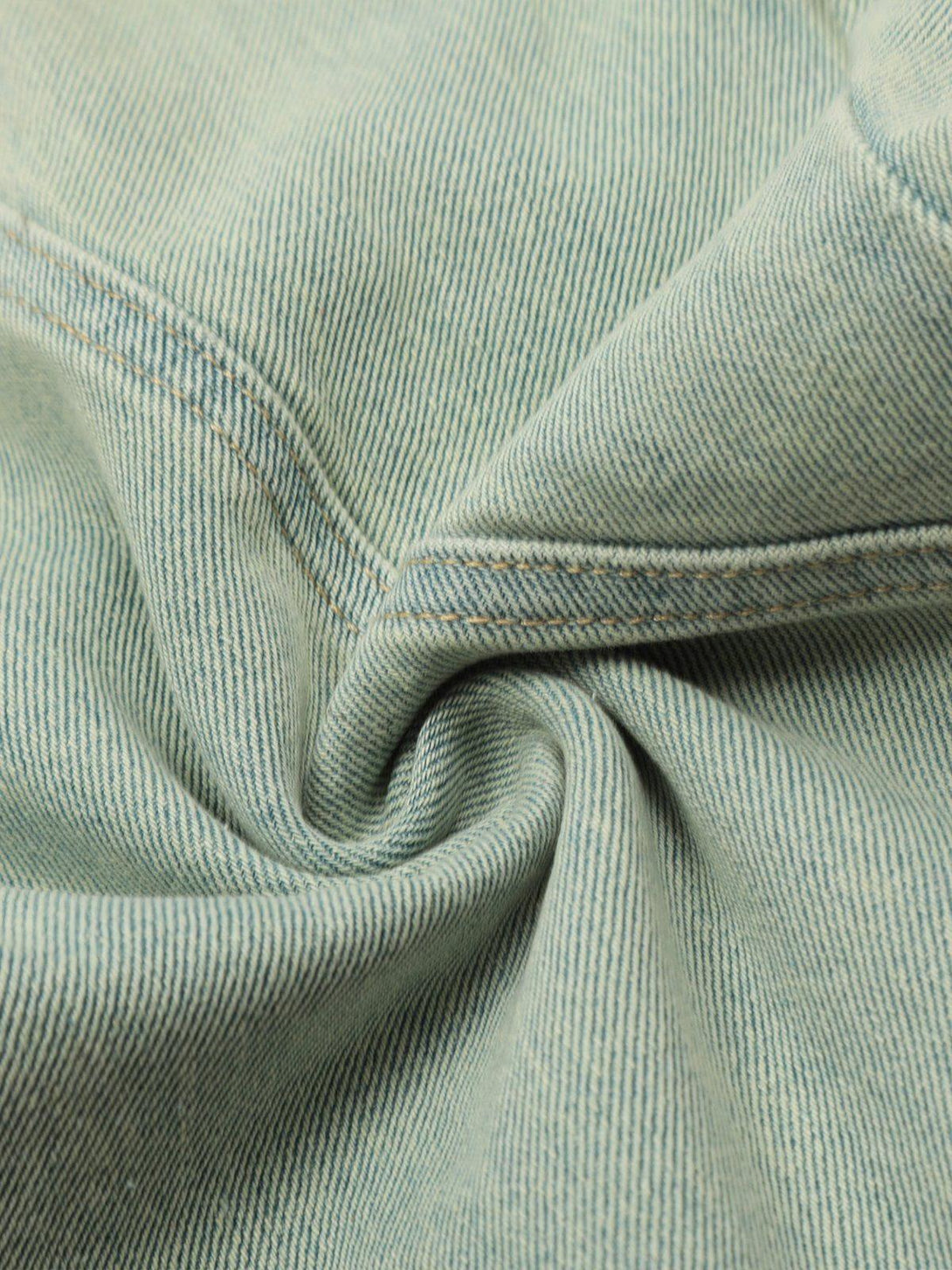 Zoomed-in texture of TALISHKO jeans, highlighting the washed fabric and stitch detail.