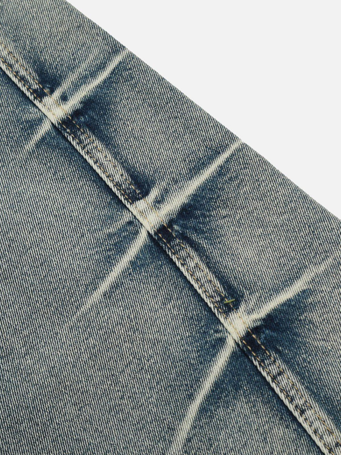 Zoomed-in texture of TALISHKO arc-stitched washed jeans, showcasing intricate stitching details.