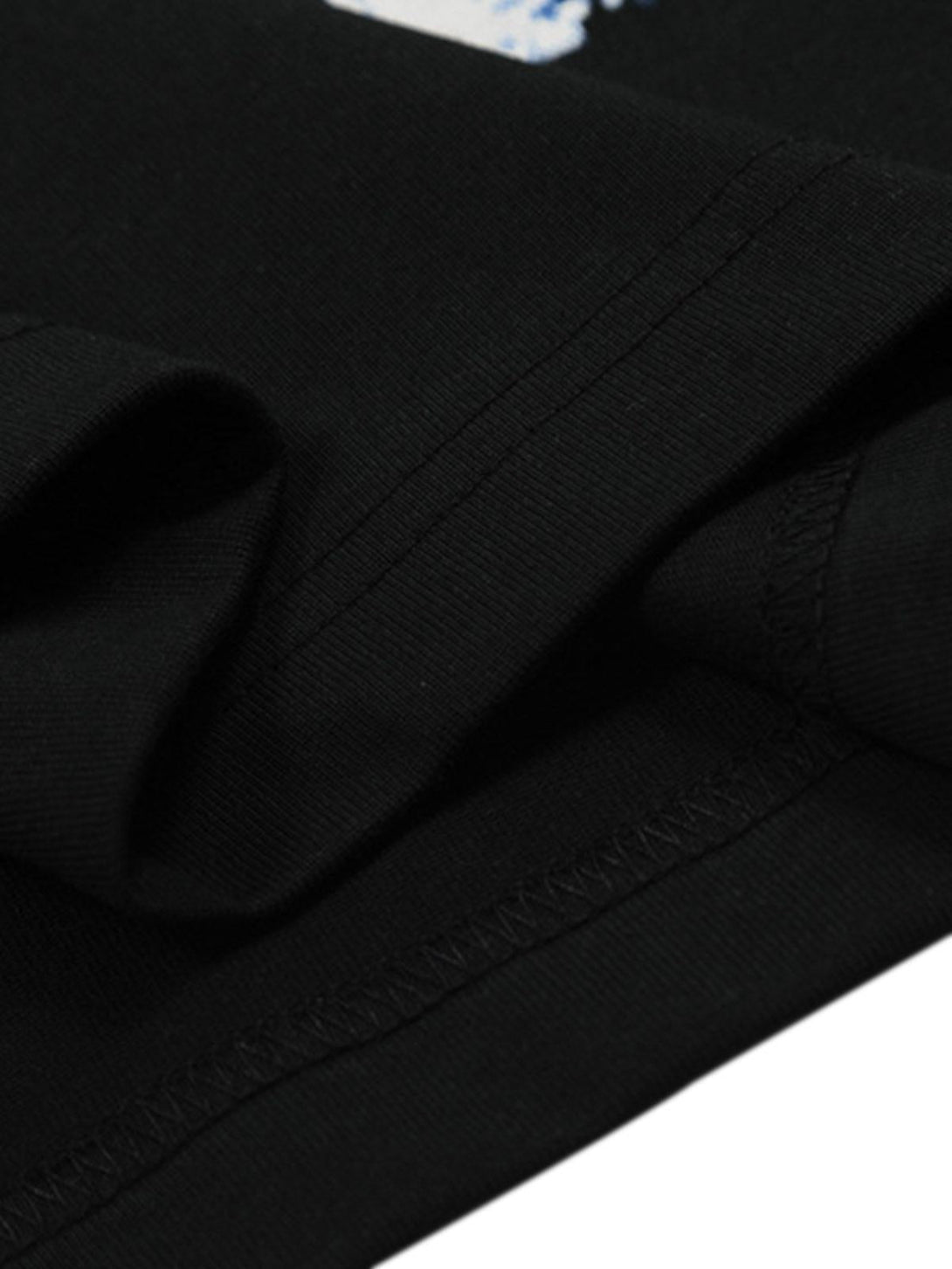 Fine stitching and fabric detail on TALISHKO's black T-shirt, emphasizing craftsmanship.