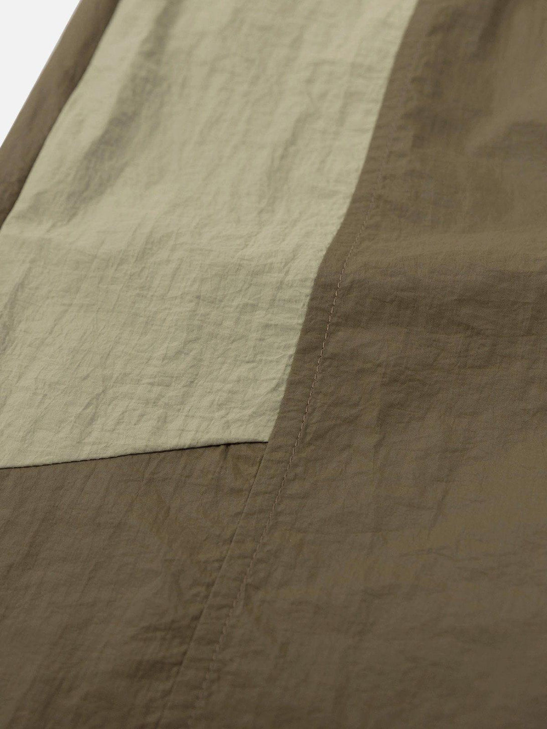 A detailed view of TALISHKO athleisure shorts, showcasing patchwork fabric and earthy tones.