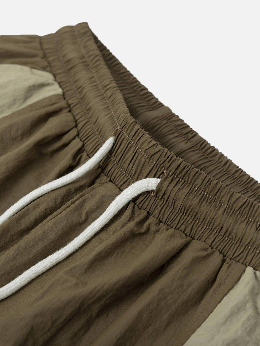 A close-up of TALISHKO athleisure shorts, highlighting the patchwork design and elastic waistband.