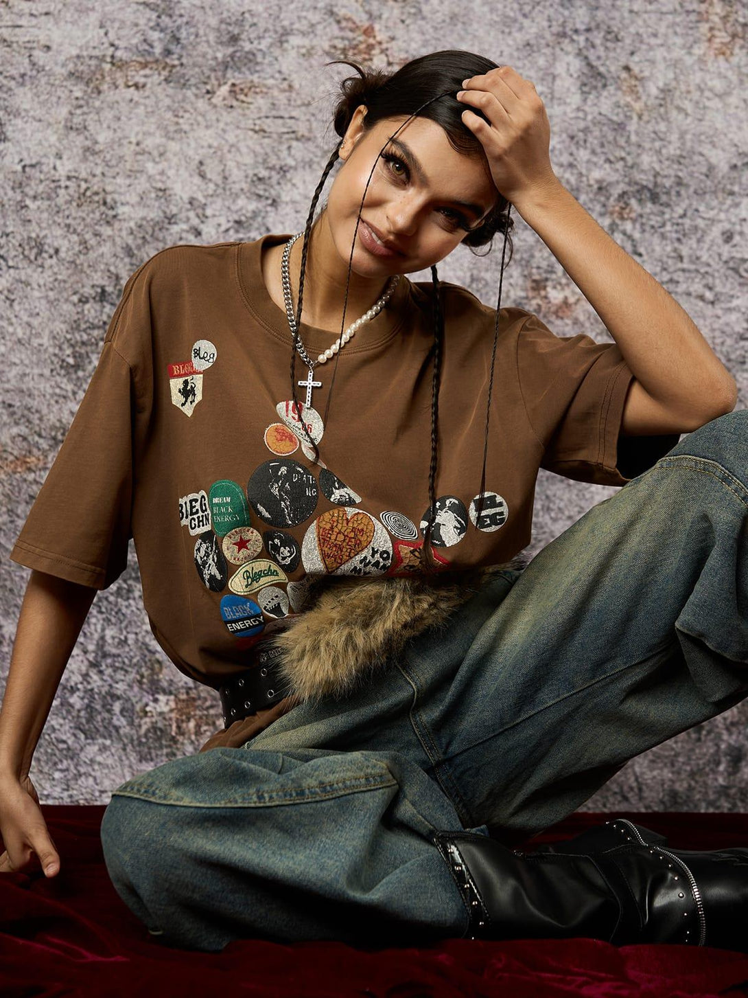 Model in a brown TALISHKO tee with badge print, paired with jeans for a relaxed vibe.