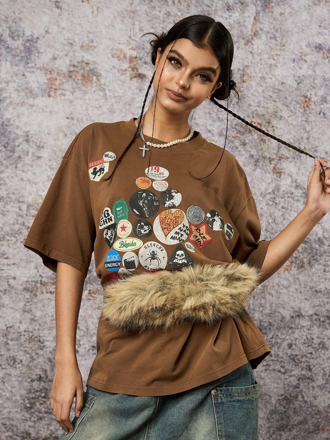 Model wearing a brown TALISHKO T-shirt with badge prints and faux fur detail, perfect for laid-back style.