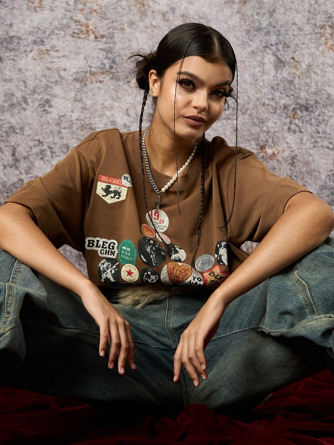 Model wearing a brown TALISHKO tee with badge print, styled for a relaxed summer vibe.