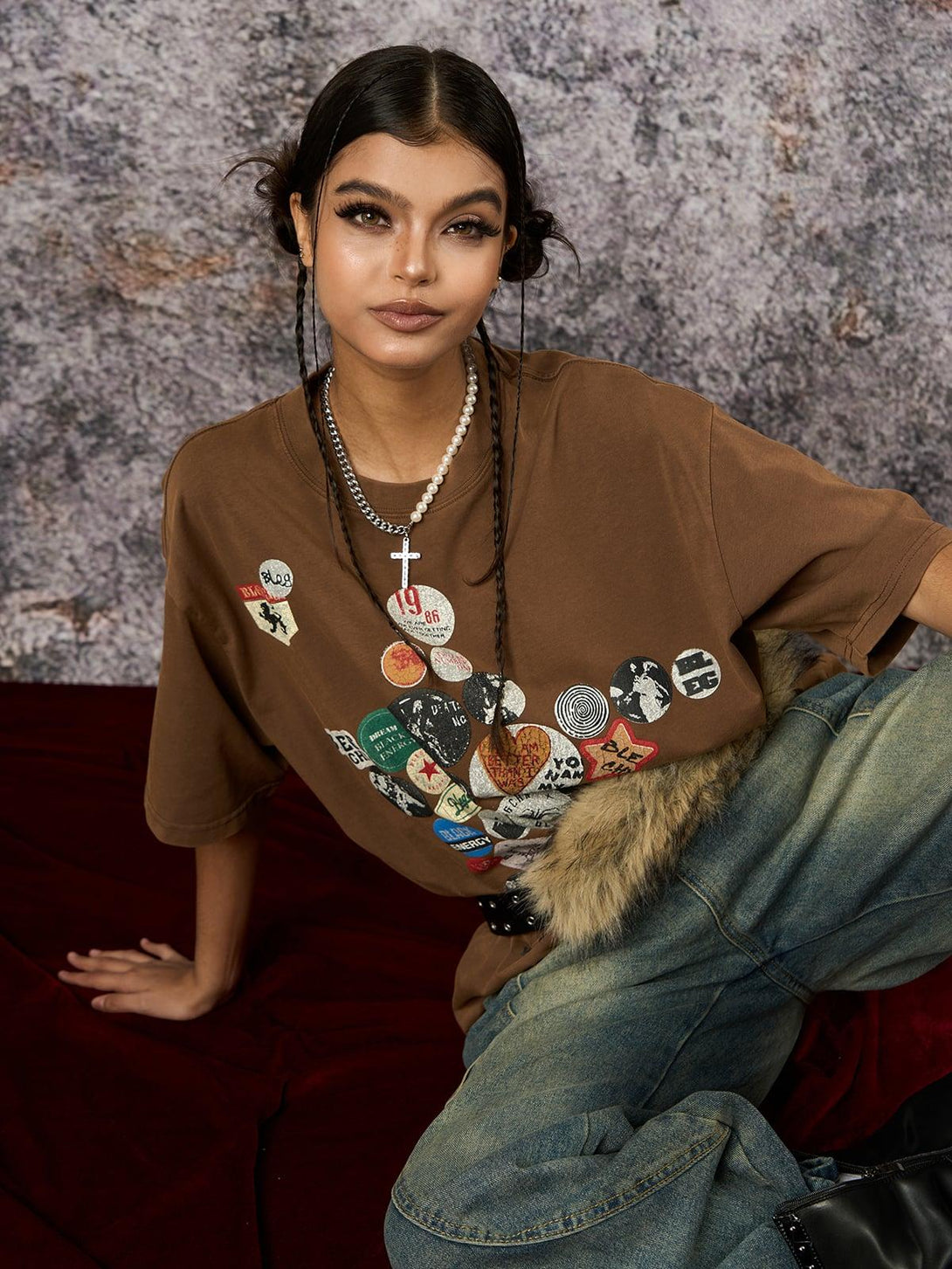 Model wears brown TALISHKO T-shirt with badge print and pearl necklace, embodying casual chic.