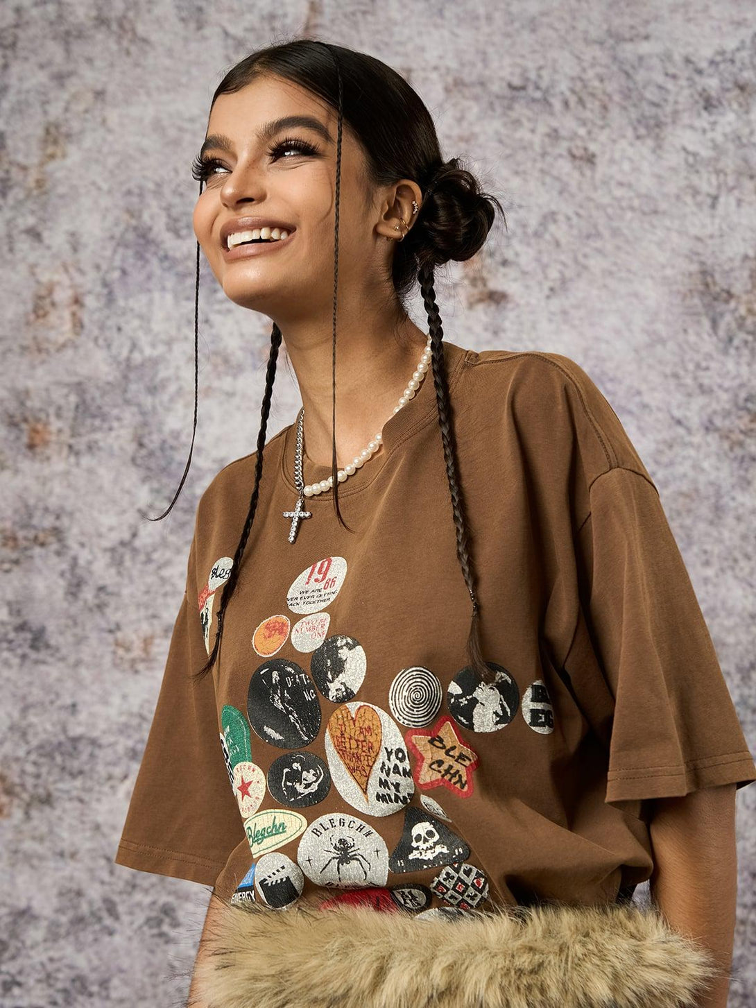 Model wearing a brown TALISHKO T-shirt with badge print, styled with faux fur for a trendy look.