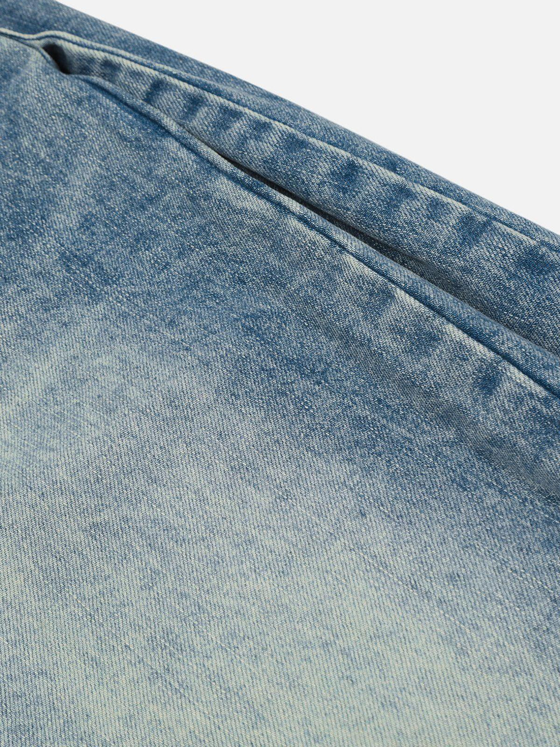 A detailed view of TALISHKO barrel baggy jeans, showcasing the unique faded denim texture.