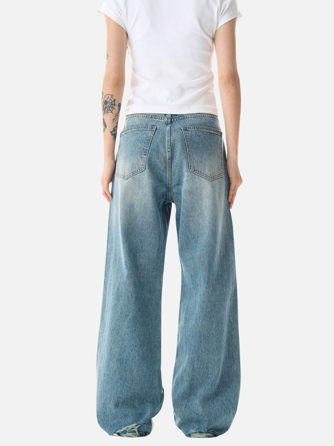 Model in blue loose distressed jeans by TALISHKO, viewed from the back, highlighting casual style.