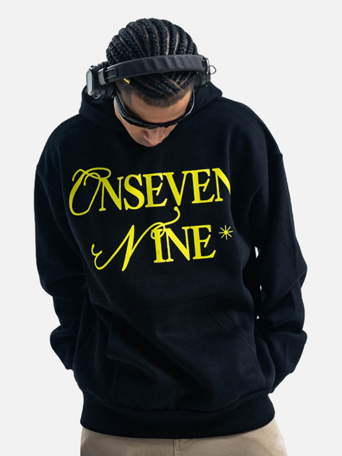 Model wearing a black fleece hoodie by TALISHKO, featuring bold yellow lettering for a modern vibe.