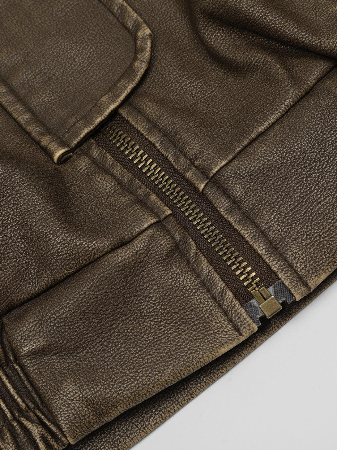 A close-up of the zipper and pocket detail on a faux leather jacket by TALISHKO.