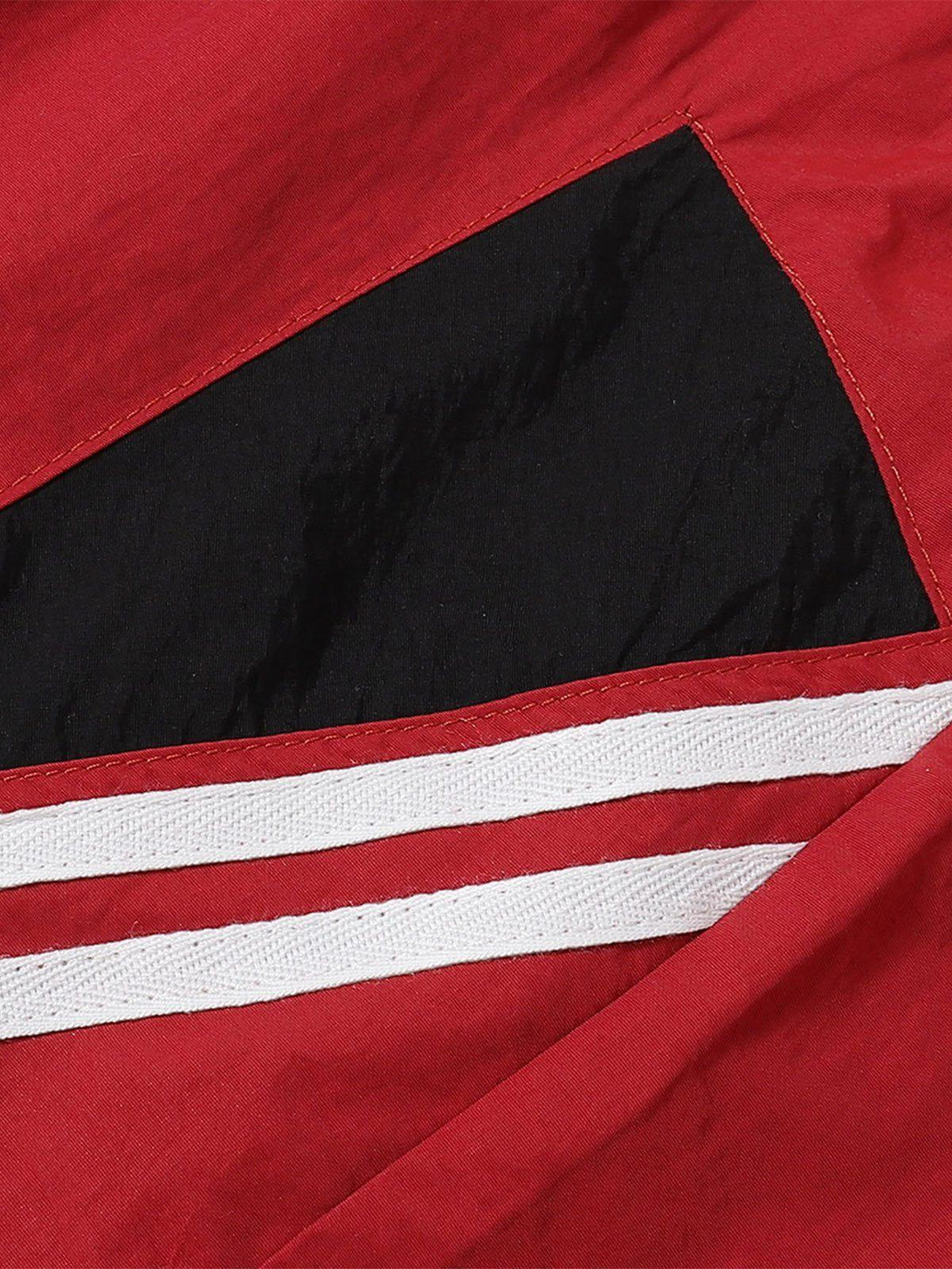 Detailed fabric and stitching of TALISHKO red shorts, featuring black and white stripe accents.