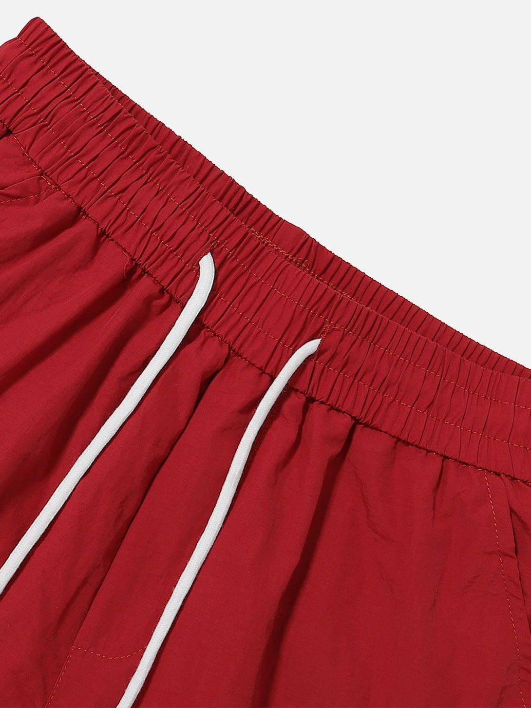 A detailed view of TALISHKO red shorts showcases the elastic waistband and drawstring ties.