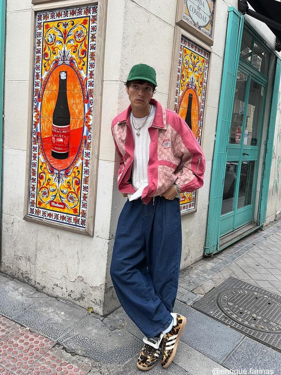 Model in TALISHKO baggy jeans, paired with a pink jacket and sneakers against a vibrant street mural.