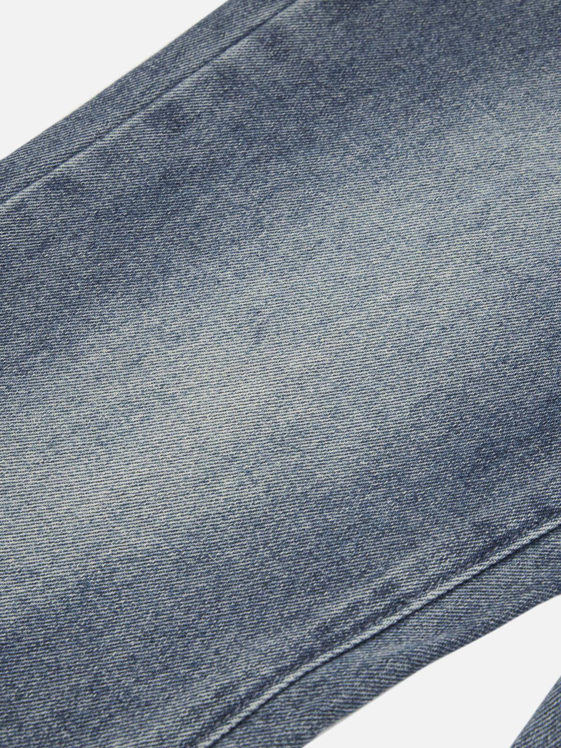 A detailed view of TALISHKO's washed denim texture, highlighting the classic low-rise style.