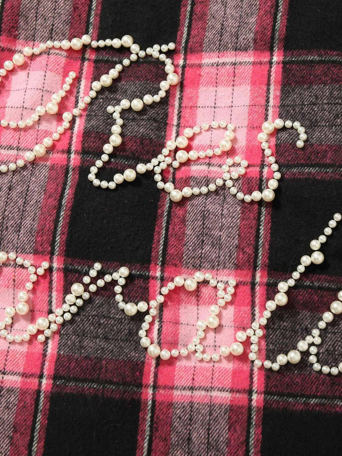 Intricate look at pearl bead detailing on a pink plaid fabric from TALISHKO's collection.