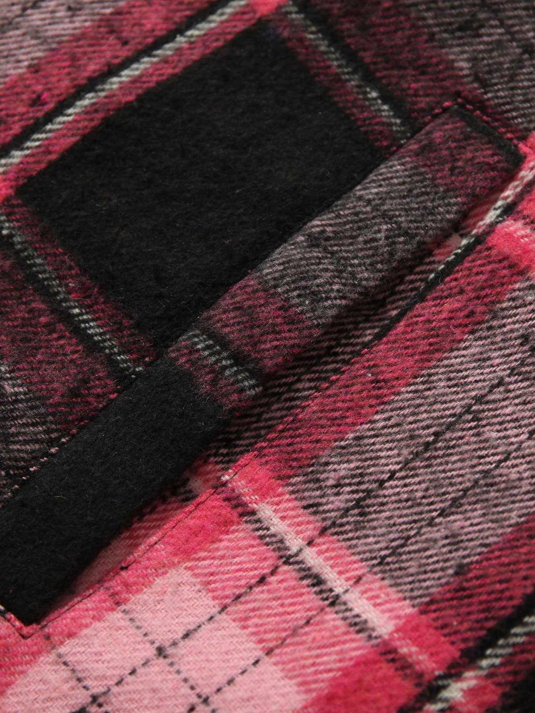 Zoomed-in texture of pink plaid fabric with intricate detailing on a jacket by TALISHKO.