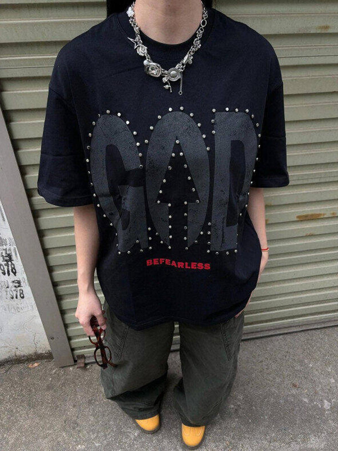Model wearing a black "BEFEARLESS" T-shirt with bold design, paired with casual pants, by TALISHKO.