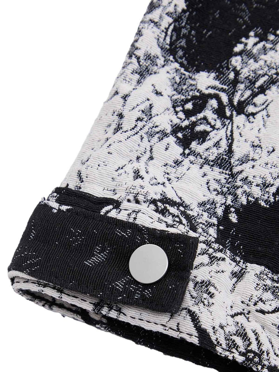 A tight crop highlighting the button detail on TALISHKO's black and white floral denim jacket.