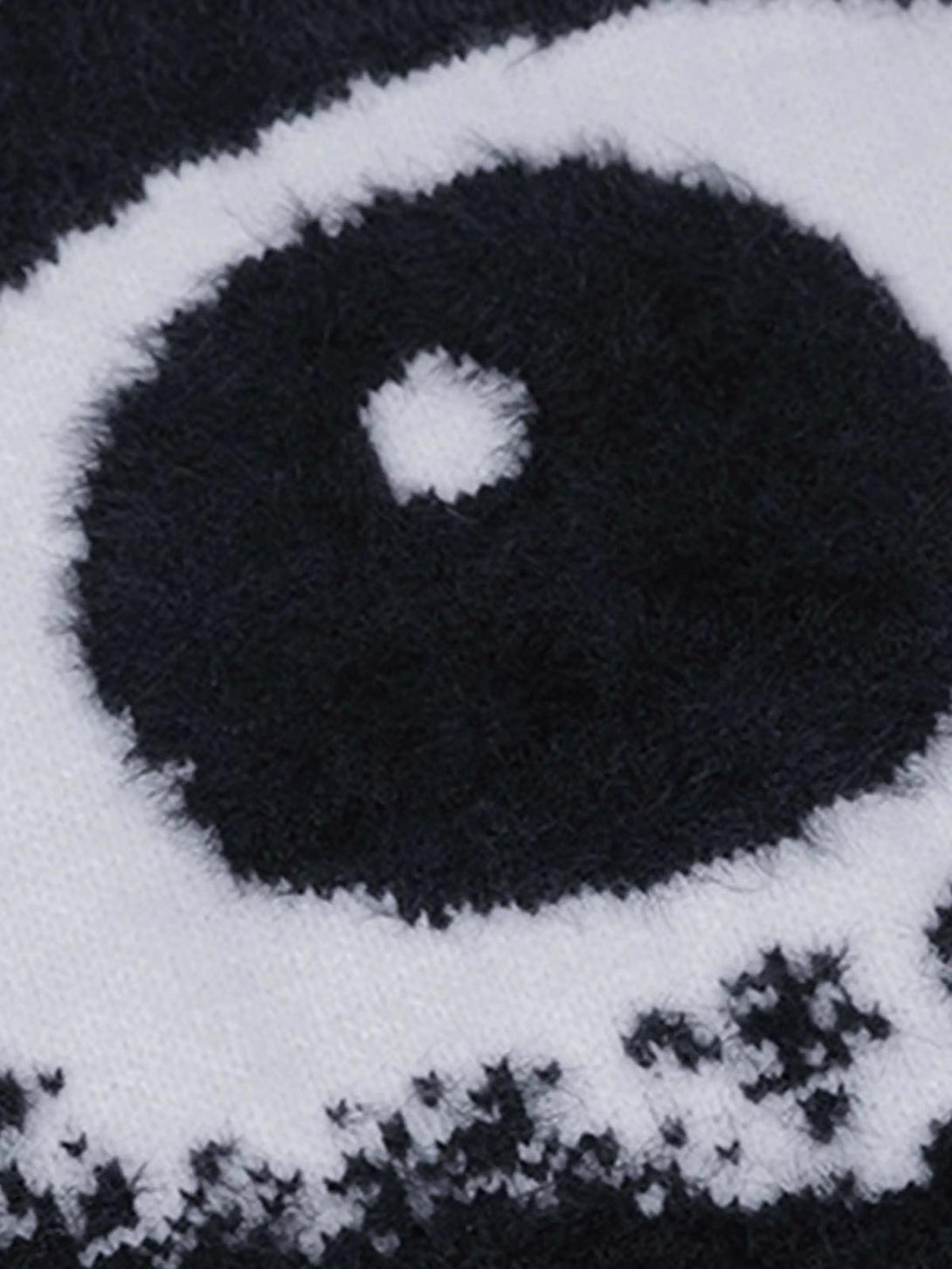 Zoomed-in texture of TALISHKO's black sweater, featuring a bold eye pattern design.