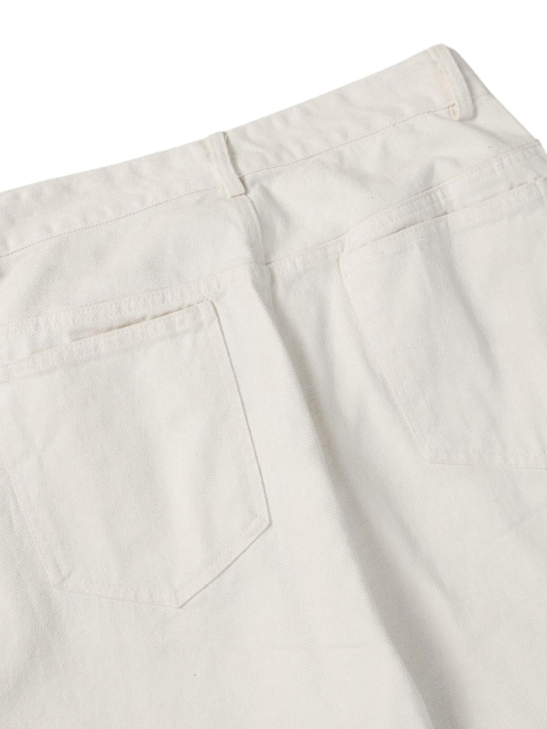 Detailed look at the back pockets of white jeans by TALISHKO, highlighting casual style.