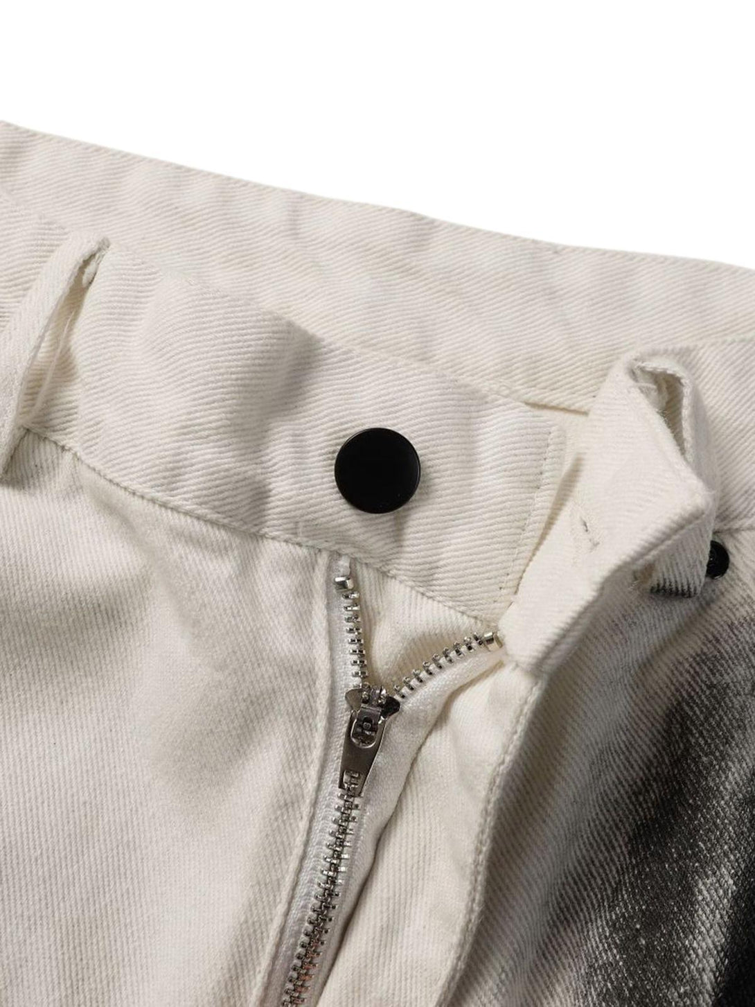 A tight crop highlighting TALISHKO's white jeans zipper and button detail with black stain design.