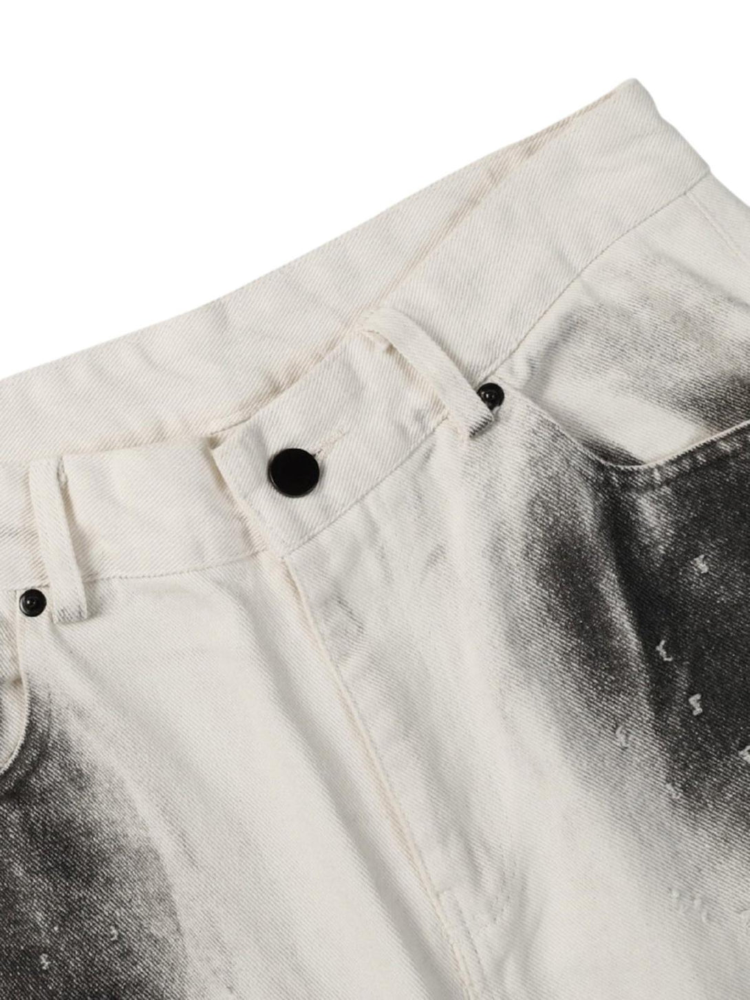 A detailed view of TALISHKO jeans, showcasing a black stain effect on white denim fabric.