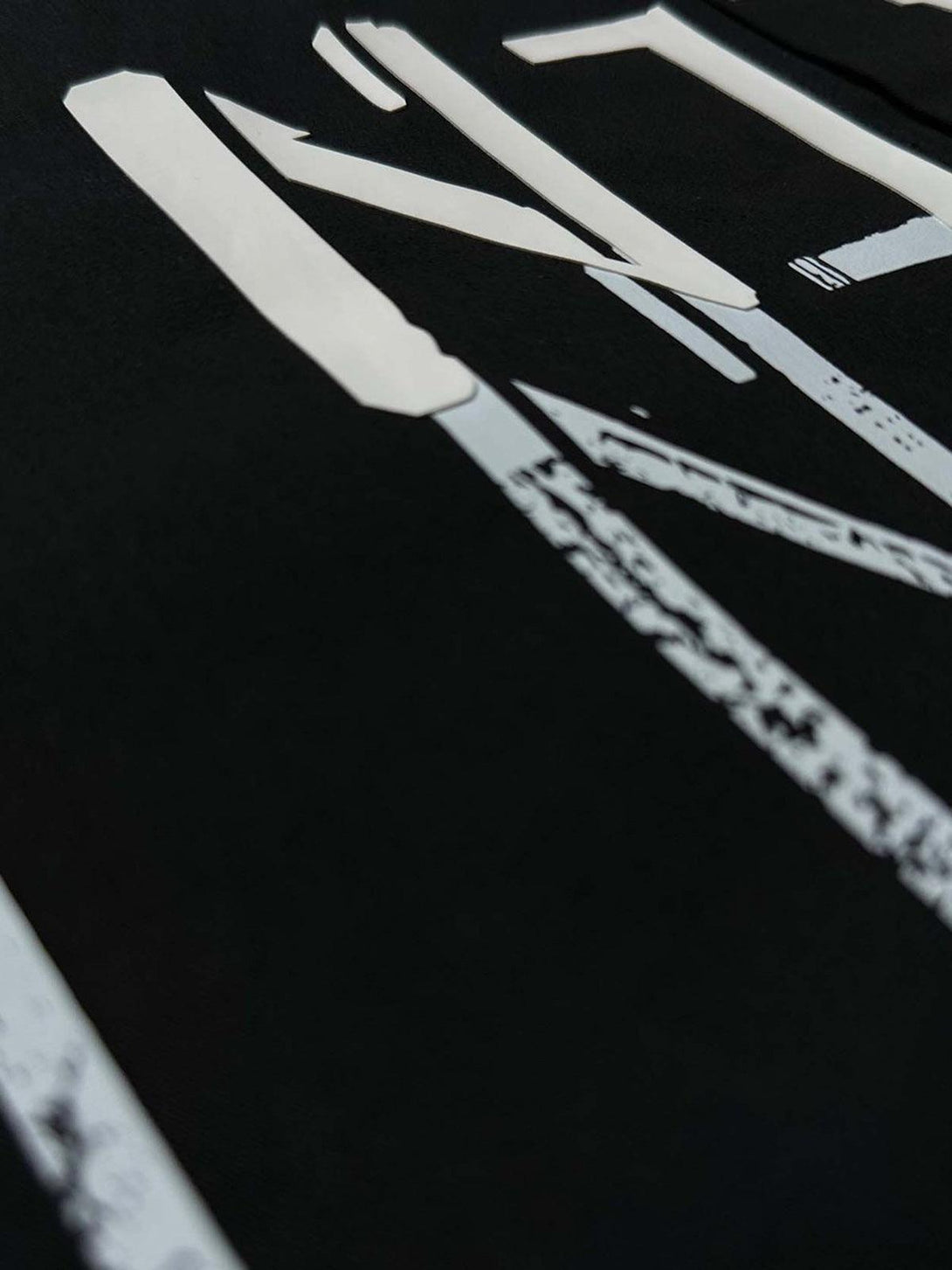 Zoomed-in texture of a bold letter graphic on a short-sleeve shirt by TALISHKO.
