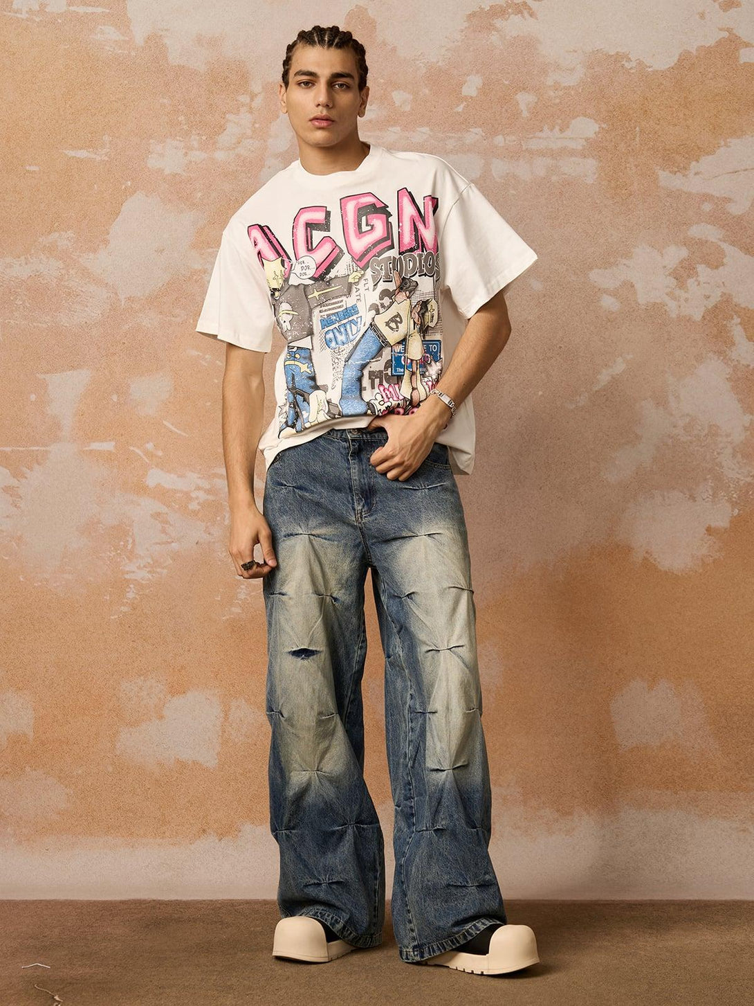 Model wearing a vibrant graphic T-shirt and wide jeans by TALISHKO, embracing streetwear style.