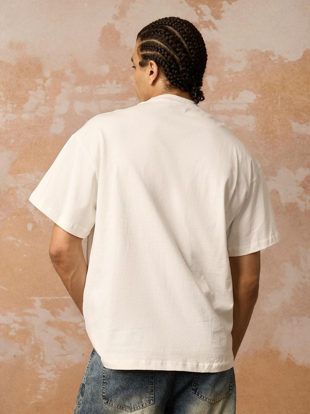 Model in a white graphic T-shirt by TALISHKO, showcasing bold streetwear from the back view.