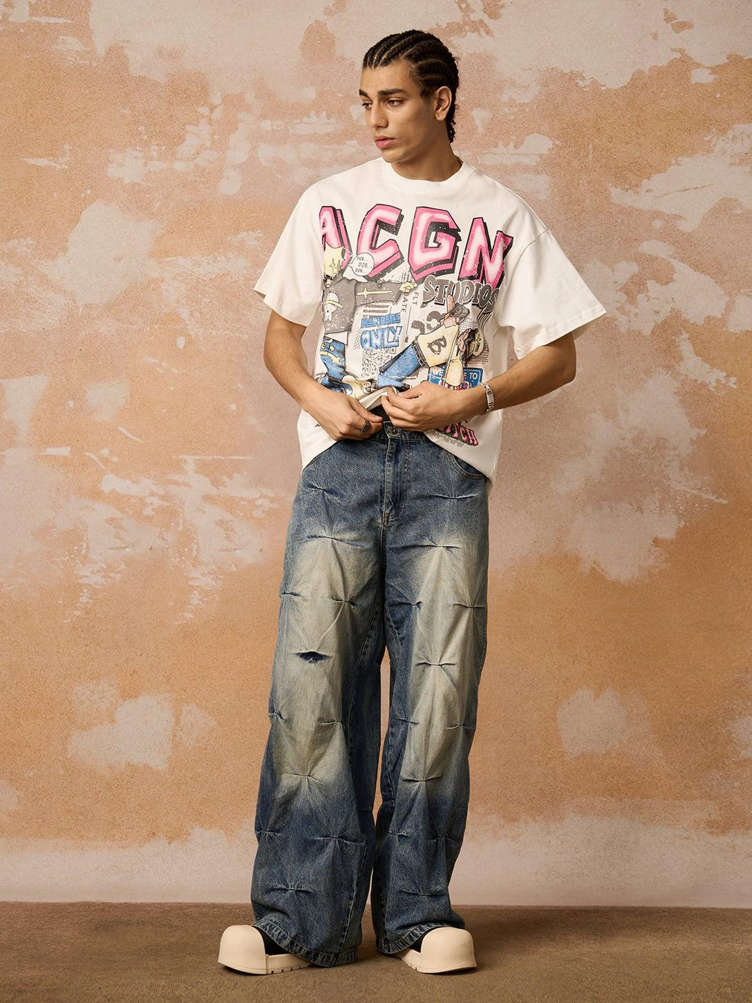 Model in a white graphic T-shirt and baggy jeans by TALISHKO, highlighting bold streetwear flair.