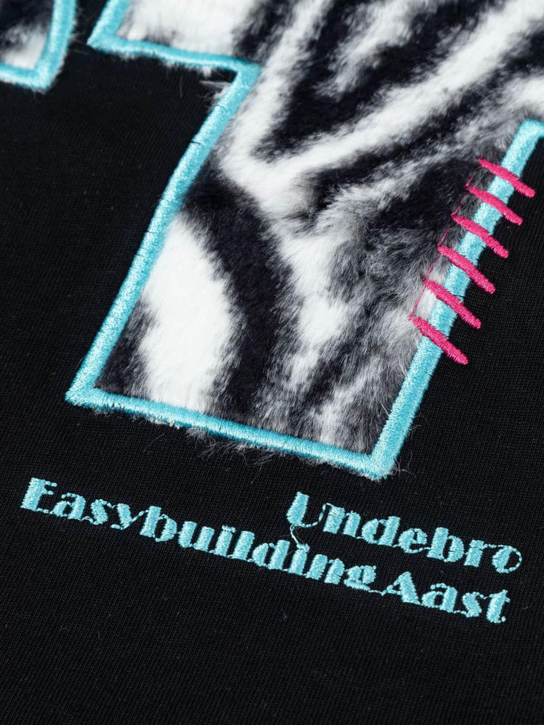 Intricate design detail with zebra print and turquoise accents on a TALISHKO graphic T-shirt.