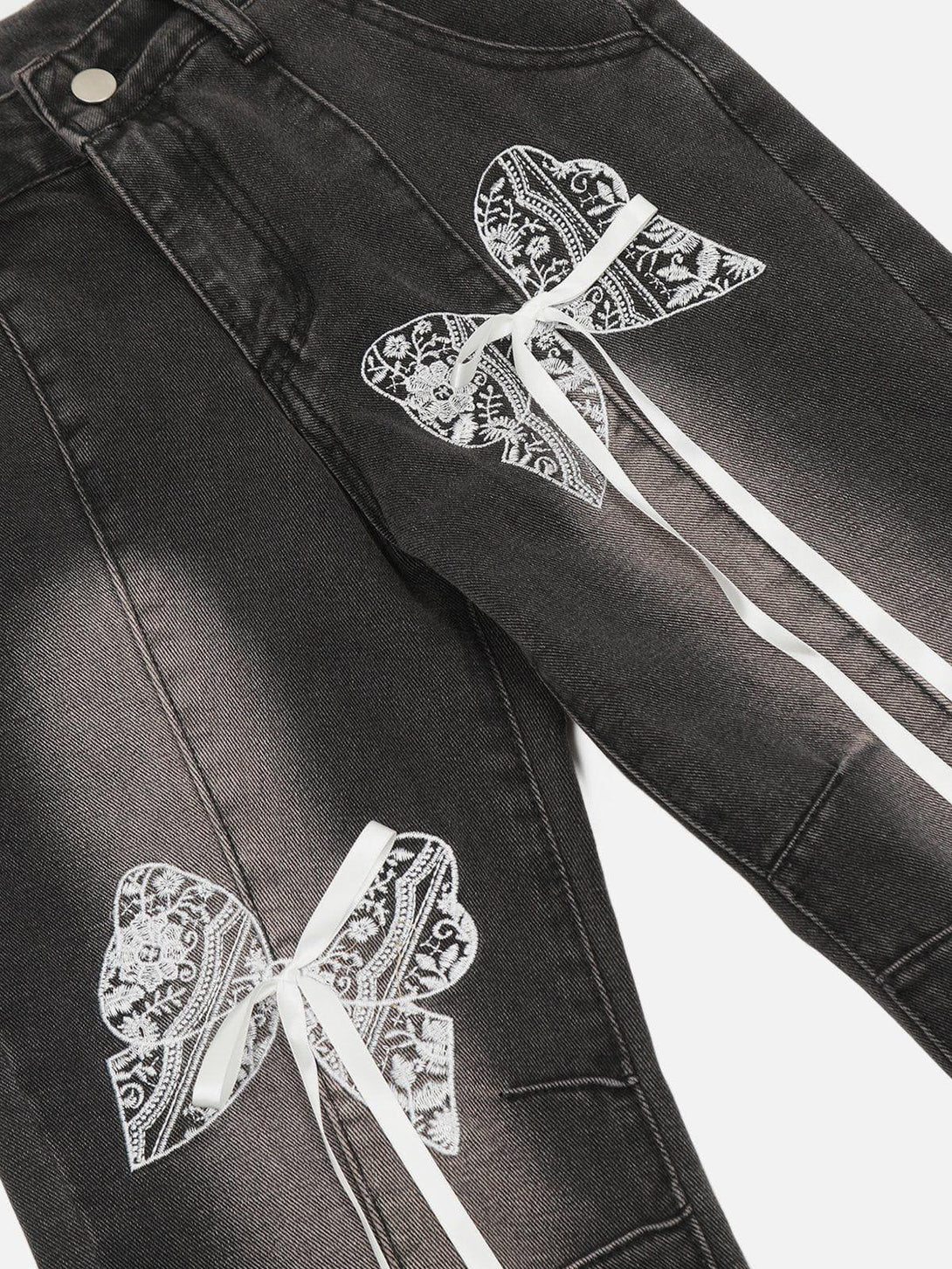 A close-up of TALISHKO's black washed jeans with intricate lace bows, highlighting unique design details.