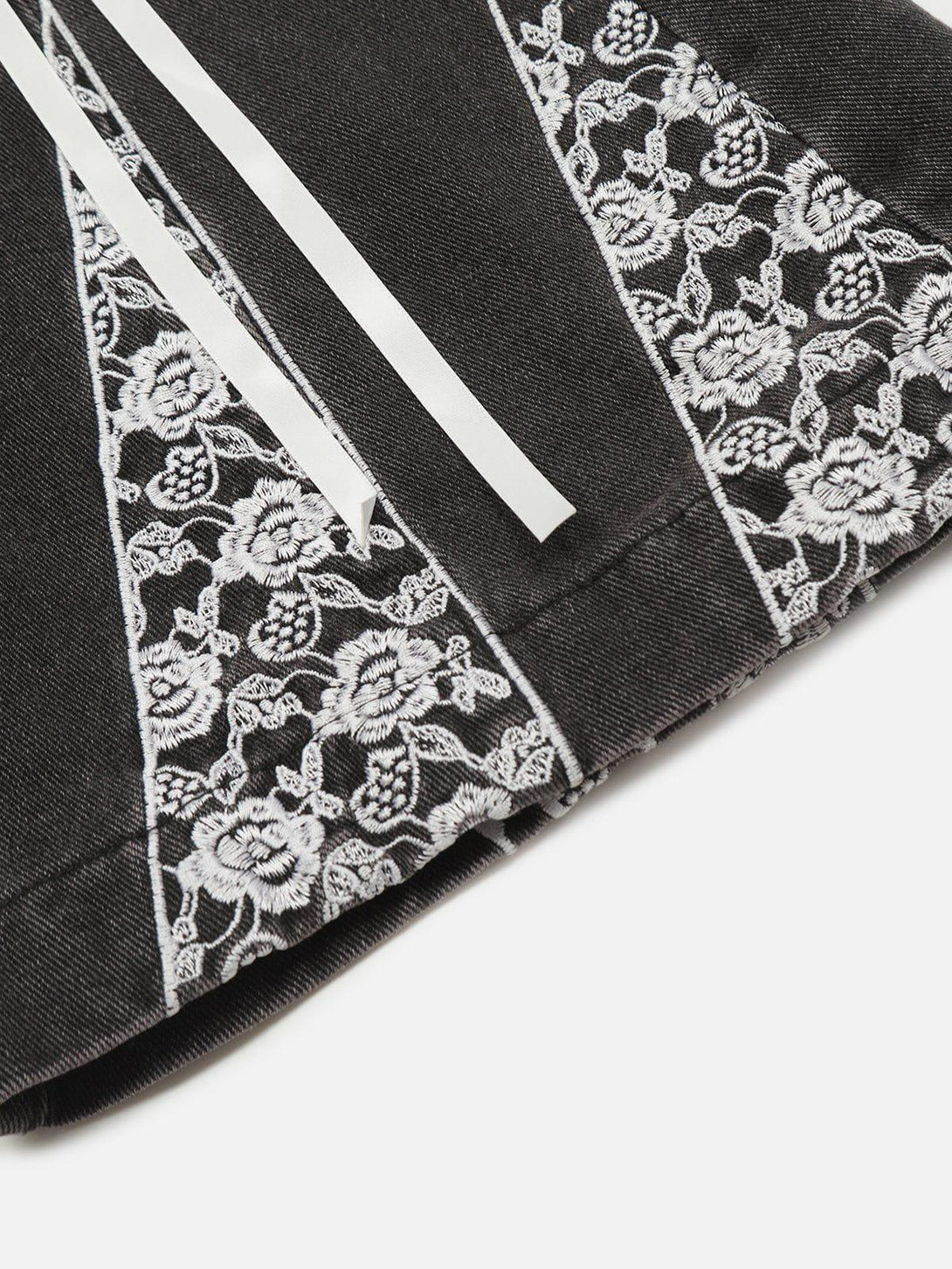 Intricate look at TALISHKO's black jeans with lace detailing and ribbon accents, enhancing style.