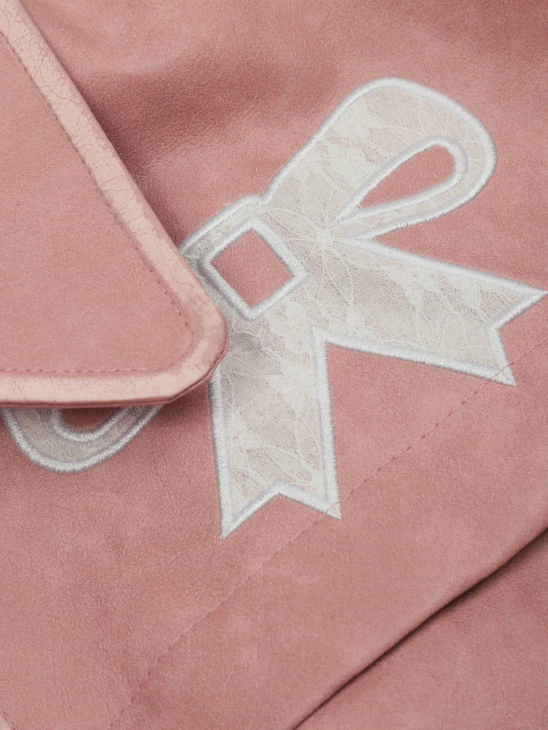 Intricate look at the pink faux leather and bow detail on a TALISHKO cropped jacket.