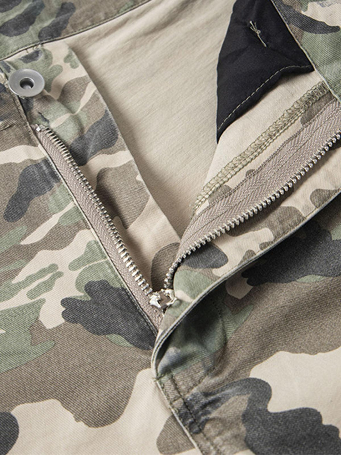 A close-up of TALISHKO camouflage cargo shorts, highlighting the zipper and fabric details.