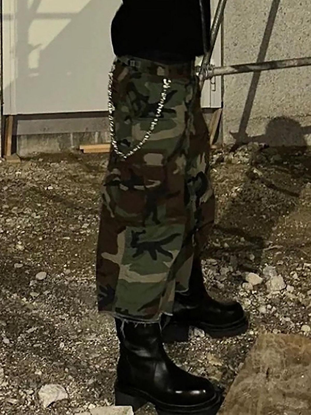 TALISHKO camouflage cropped cargo shorts with buckle waist, styled with black boots outdoors.