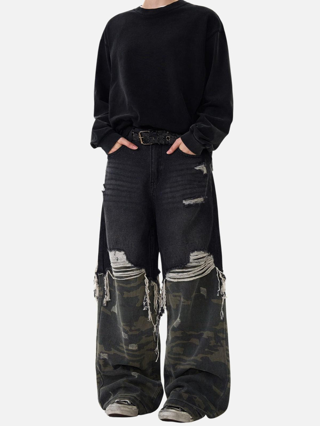 Model in TALISHKO's distressed jeans with camouflage accents, featuring a bold streetwear style.