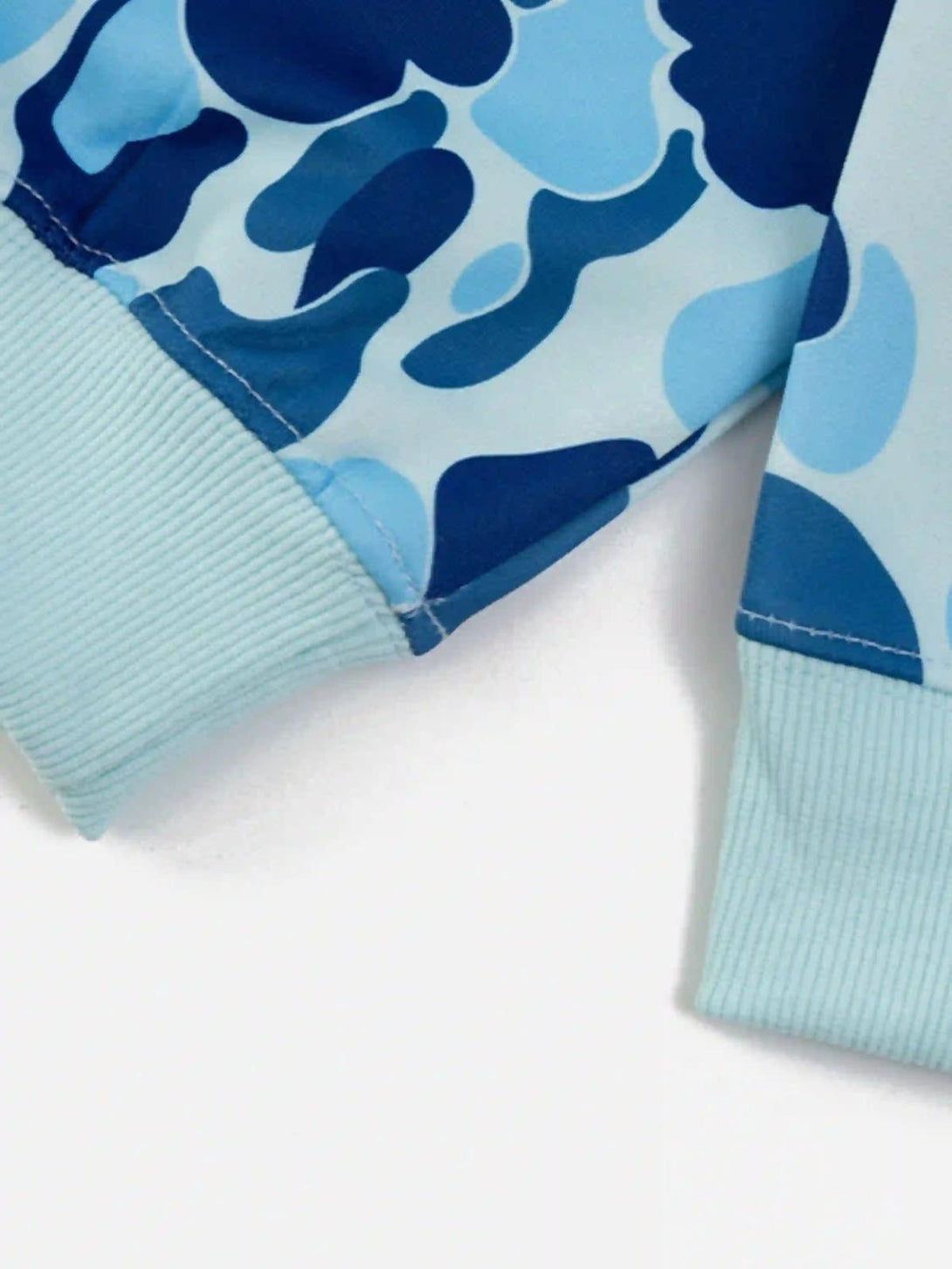 Intricate look at the blue camouflage pattern and ribbed cuffs on TALISHKO's hoodie design.